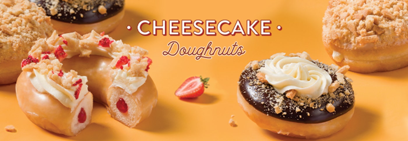 Krispy Kreme Cheesecake Doughnuts - Now available to order online or to buy in store until 29th July 2024. Cheesecake Doughnuts featuring three different types of cheesecake inspired doughnuts on a yellow background with 'Cheesecake Doughnuts' heading. Chocolate flavour, vanilla crumb flavour and strawberry flavour.